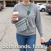 Mom wearing The Freehand crossbody bag with both hands free, holding coffee and her toddler's hand